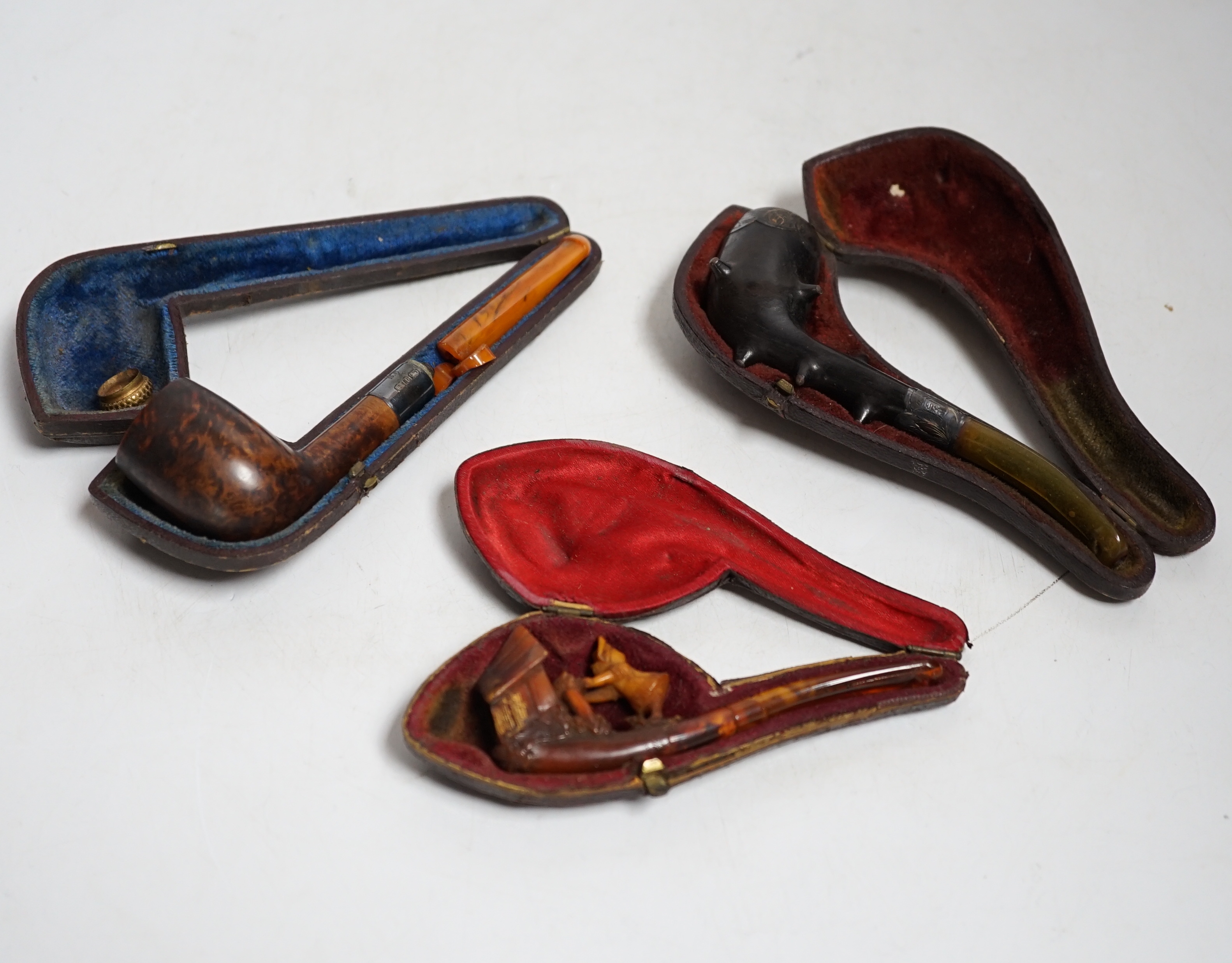 Three cased pipes, one with carved amber novelty bowl, the other two with amber pipe ends, metal mounted, together with a tortoiseshell and mother of pearl card case, Card case 10.5cm high x 8cm wide